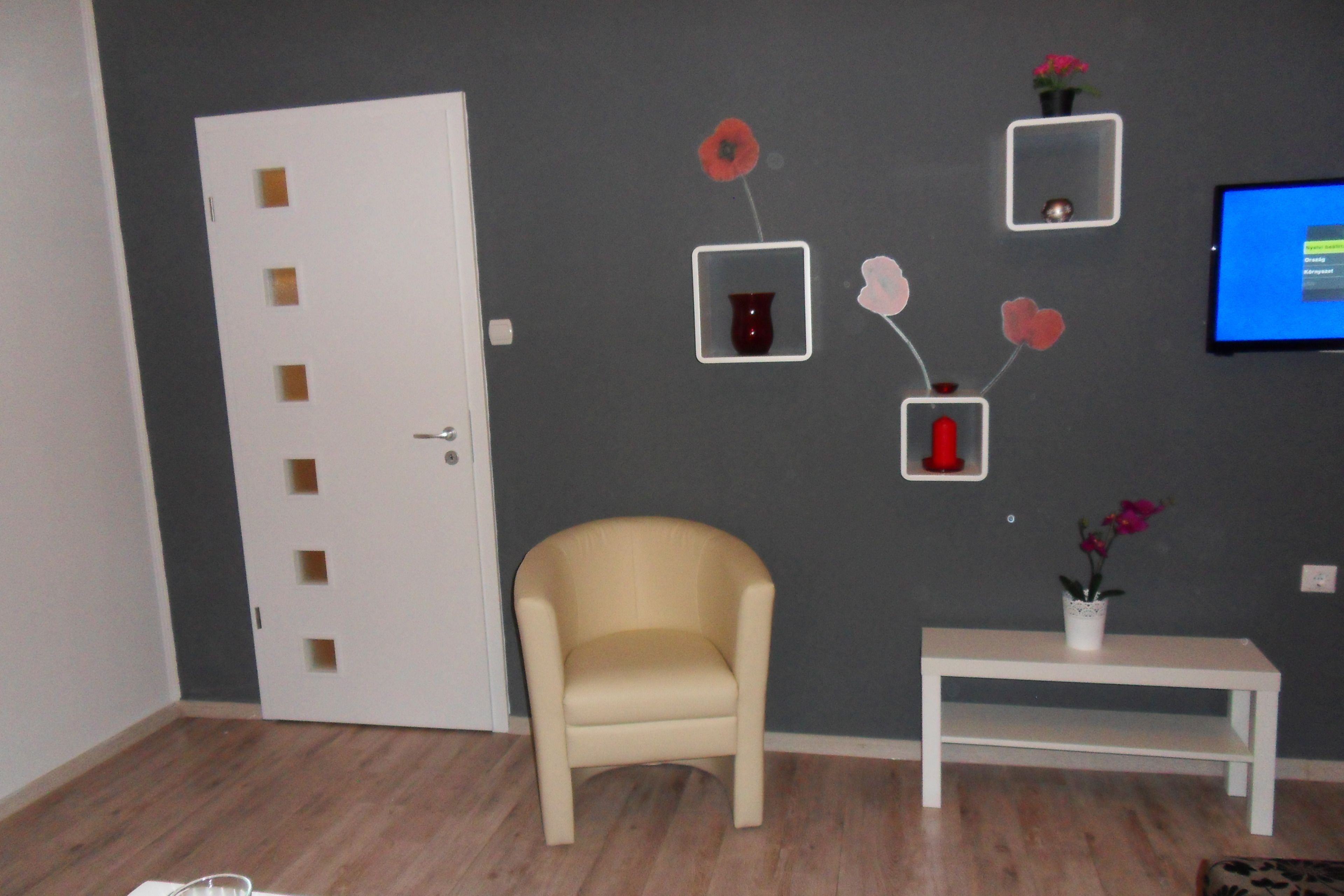 A room with a beige armchair, a white table, and a door with a small window.