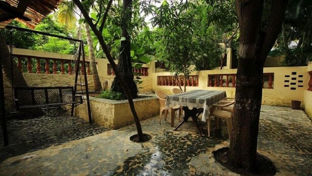 A patio area with a stone floor, a table with chairs, and a swing set.