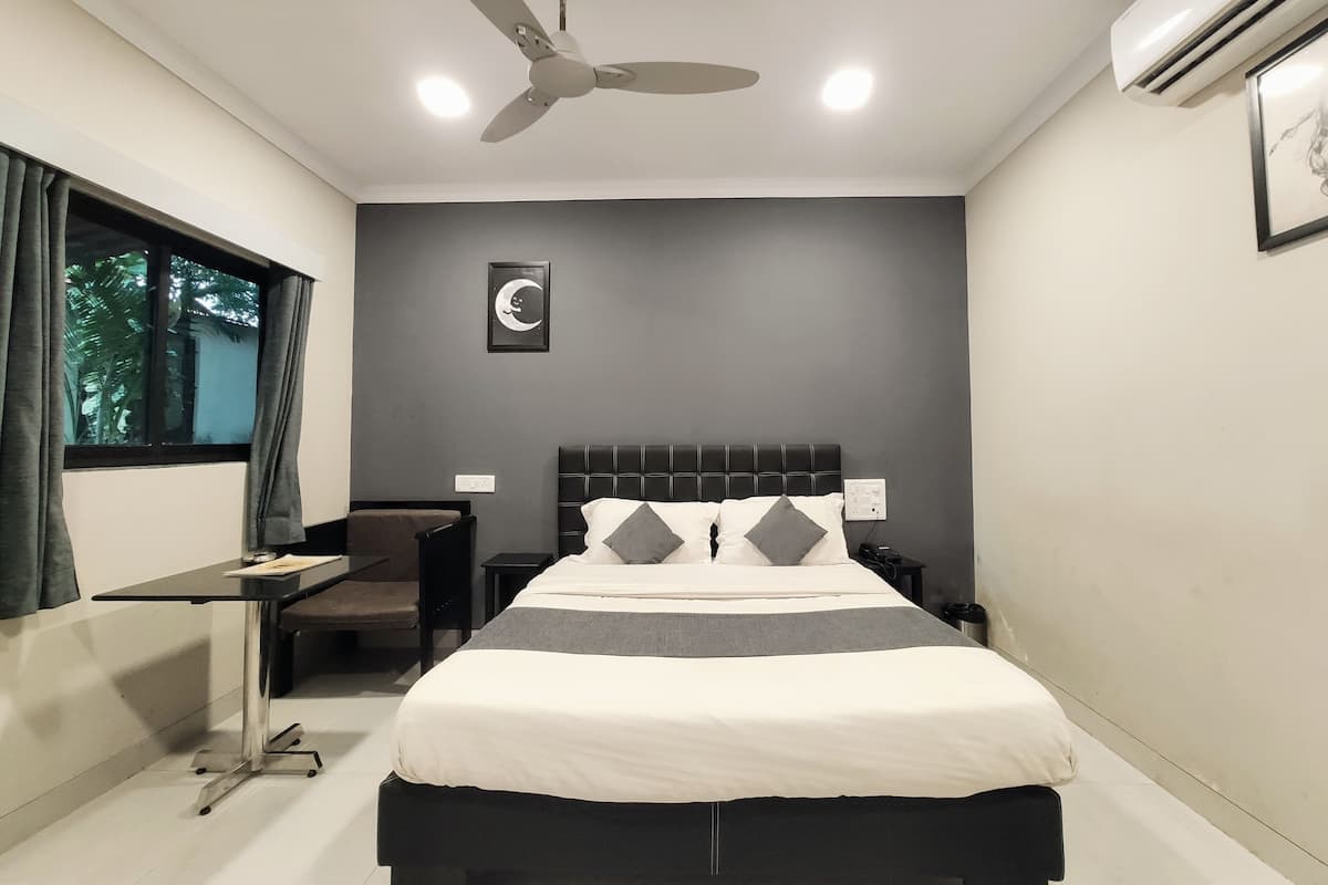 A bedroom with a bed, a desk, a chair, a ceiling fan, and an air conditioning unit.