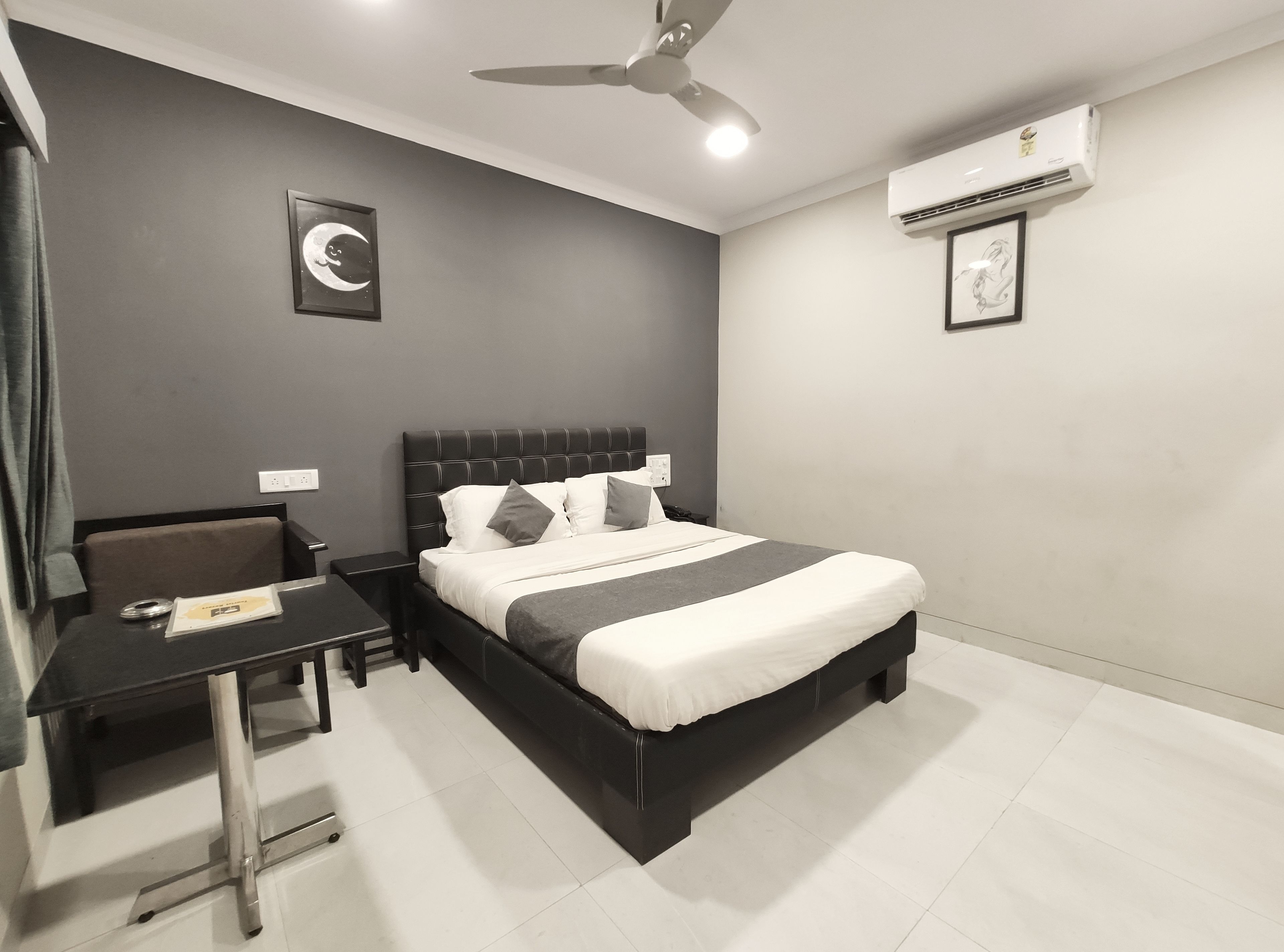 Une chambre d’hôtel moderne équipée d’un grand lit, d’un bureau, d’une chaise et d’un ventilateur de plafond.