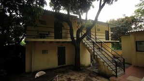A building with a staircase leading to an upper level, surrounded by trees.