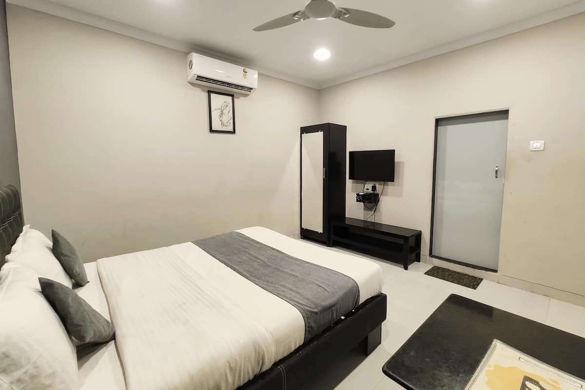 A modern hotel room with a bed, a desk, a TV, and a wardrobe.