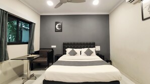 A bedroom with a bed, a desk, a chair, a ceiling fan, and an air conditioning unit.