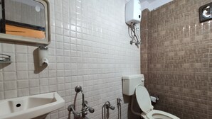 A bathroom with white tiled walls, a toilet, a sink, and a hand dryer.