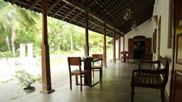 Un espace extérieur abrité, doté d’une table et de chaises, et entouré de verdure.