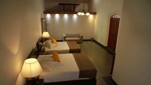 Une chambre d’hôtel avec deux lits, une chaise, une lampe et un luminaire au plafond.