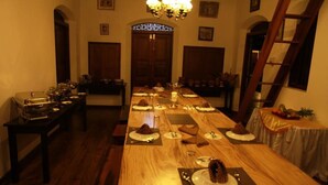 Une longue table à manger, dressée pour le repas, avec des chaises de chaque côté.