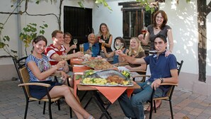 Un grupo de personas sentadas alrededor de una mesa con pescado y verduras, brindando con copas de vino.