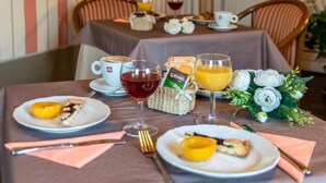 A breakfast setting with plates of food, glasses of juice and wine, and a bouquet of flowers. - Hotel Villa Liberty (Pontecurone)