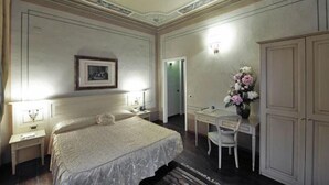 A bedroom with a large bed, a desk, a chair, and a wardrobe. - Hotel Villa Liberty (Pontecurone)