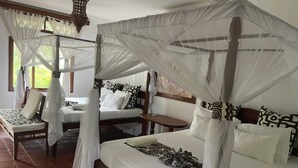 A room with four beds, each with a canopy, and a small table between them. - Mangro Hotel Diani Beach (Ukunda)