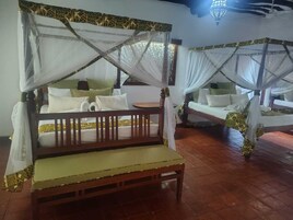 Habitación con cama de madera con dosel, un banco y una mesita.