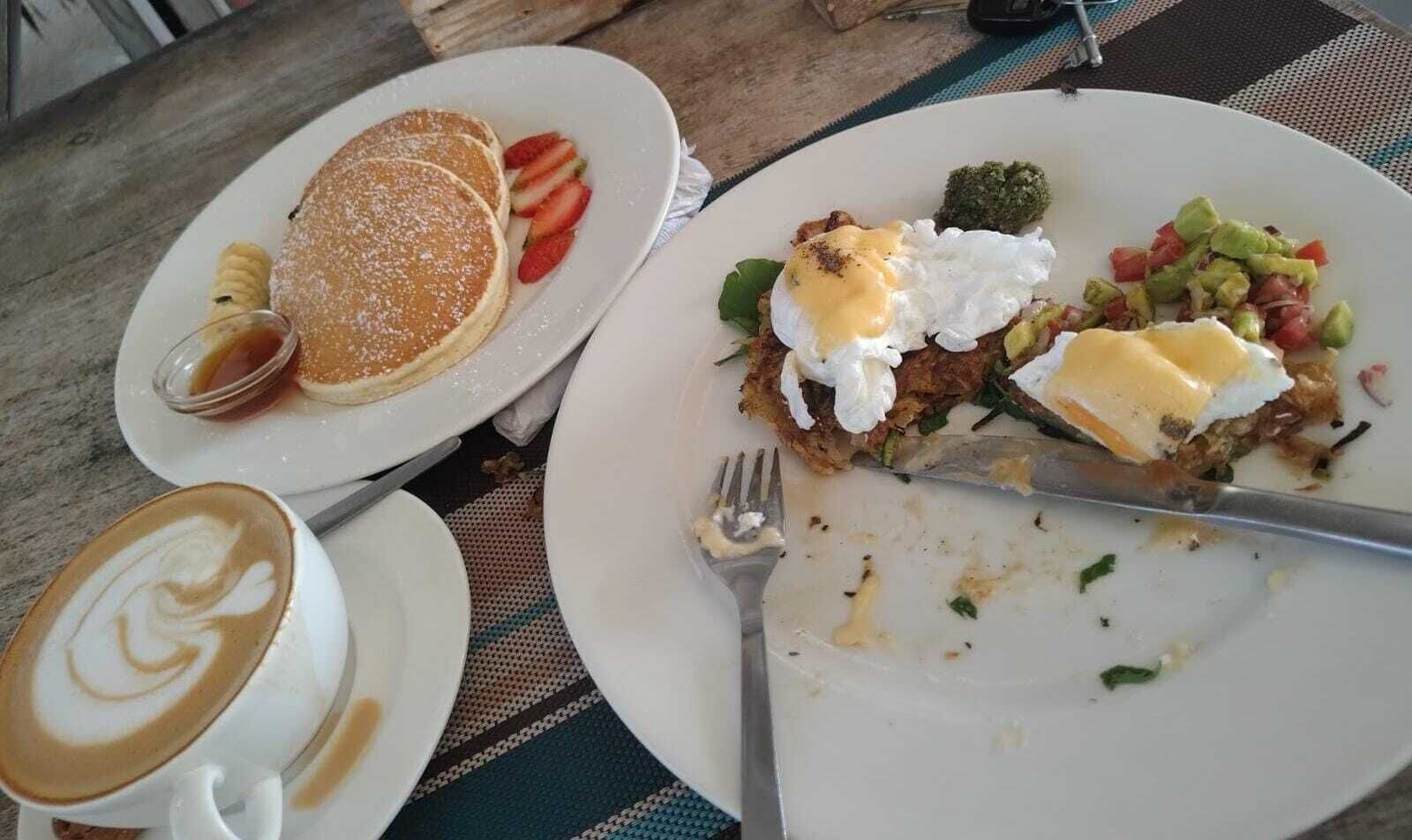 A breakfast plate with pancakes, strawberries, and a cup of coffee.