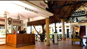 A reception area with a wooden counter and a sign that reads "RECEPTION". - Mangro Hotel Diani Beach (Ukunda)