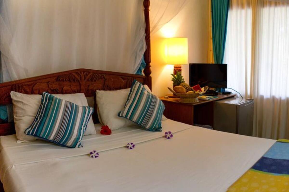 A bed with a wooden headboard, a bedside table with a lamp, and a television.