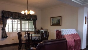 A dining area with a round table, chairs, a chandelier, a window with curtains, and a painting on the wall. - Yuan Zhong Yuan B&B (Luye)