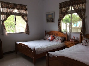 A bedroom with two wooden beds, a nightstand, and a window with curtains. - Yuan Zhong Yuan B&B (Luye)