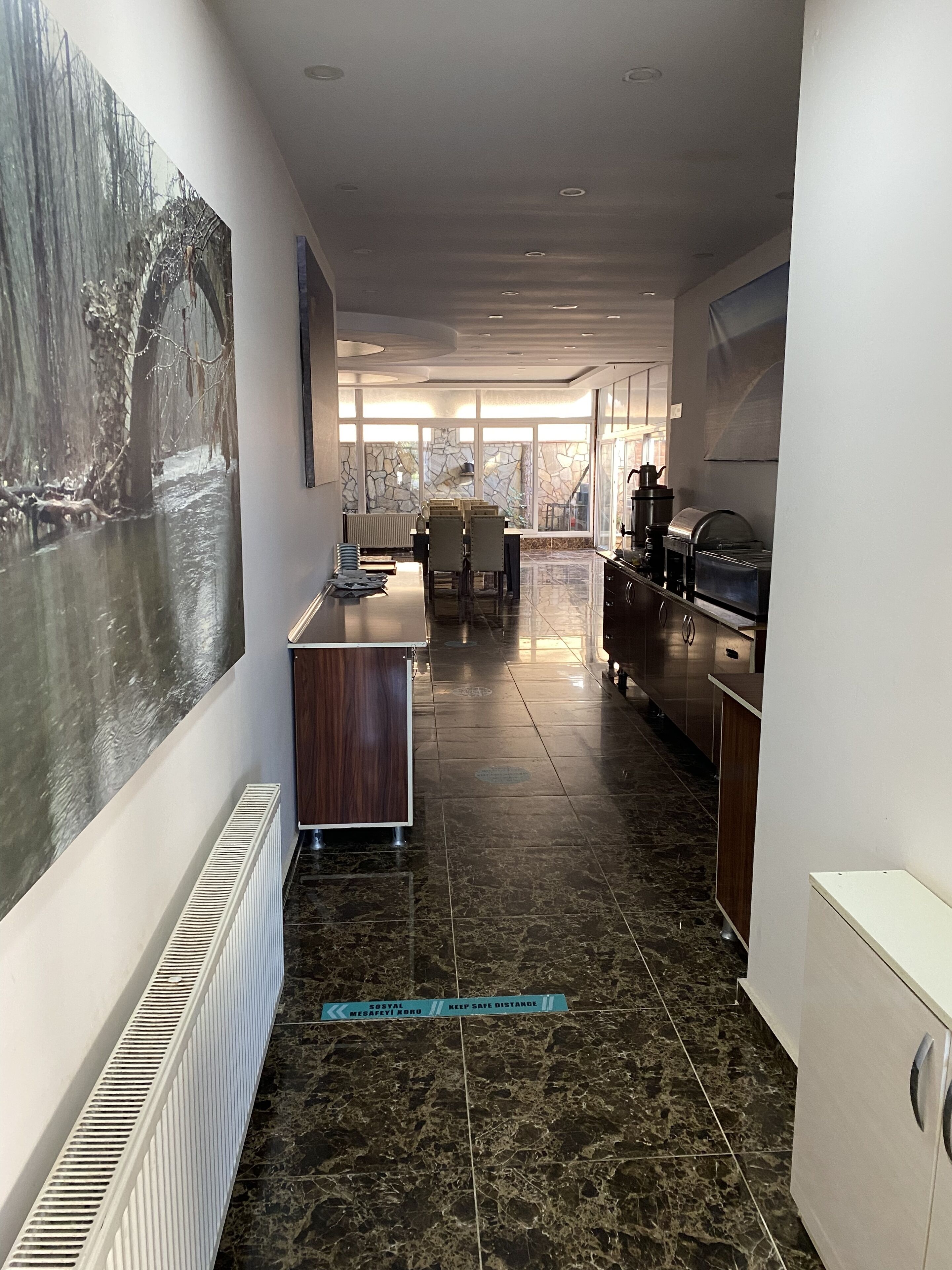 A modern kitchen with a stone backsplash, a dining area with chairs, and a view through large windows.