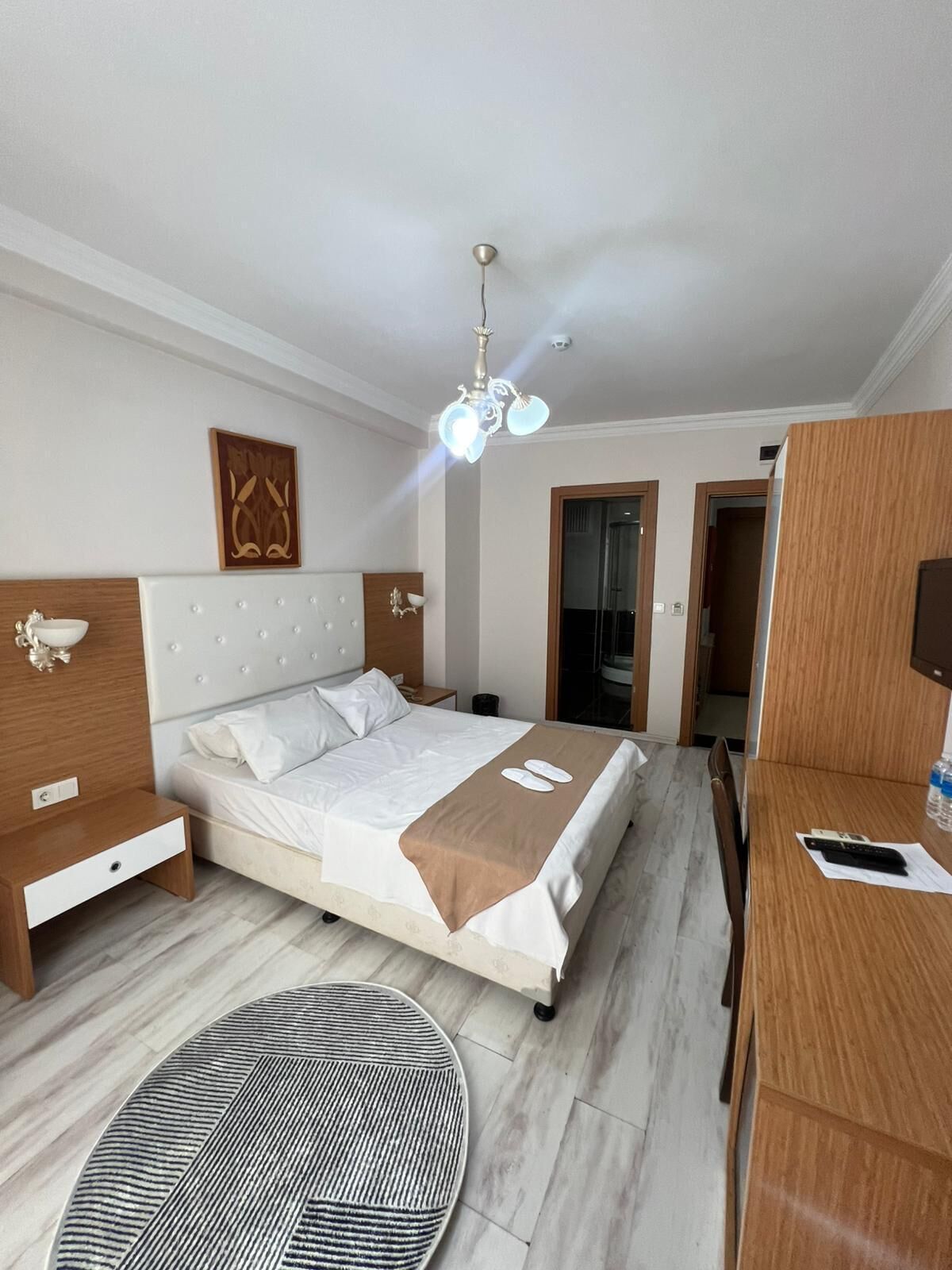 Une chambre d’hôtel avec un lit, une table de chevet, une lampe et un tapis rond.