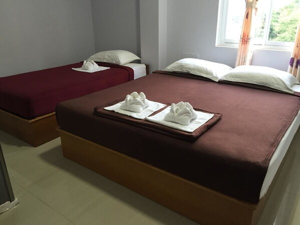 A hotel room with two beds, each with white pillows and towels.