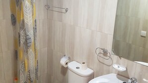 Um banheiro com vaso sanitário, pia e espelho.