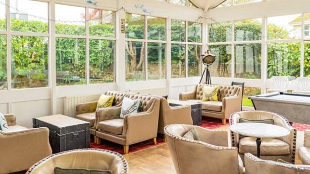A sunlit room with large windows, a pool table, and comfortable seating. - Woodlands Hotel (Sidmouth)