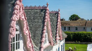A building with ornate pink architectural details, a stone facade, and a well-maintained garden. - Woodlands Hotel (Sidmouth)