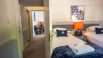 Camera d'albergo con due letti, un comodino con una lampada, una sedia e un quadro appeso al muro.