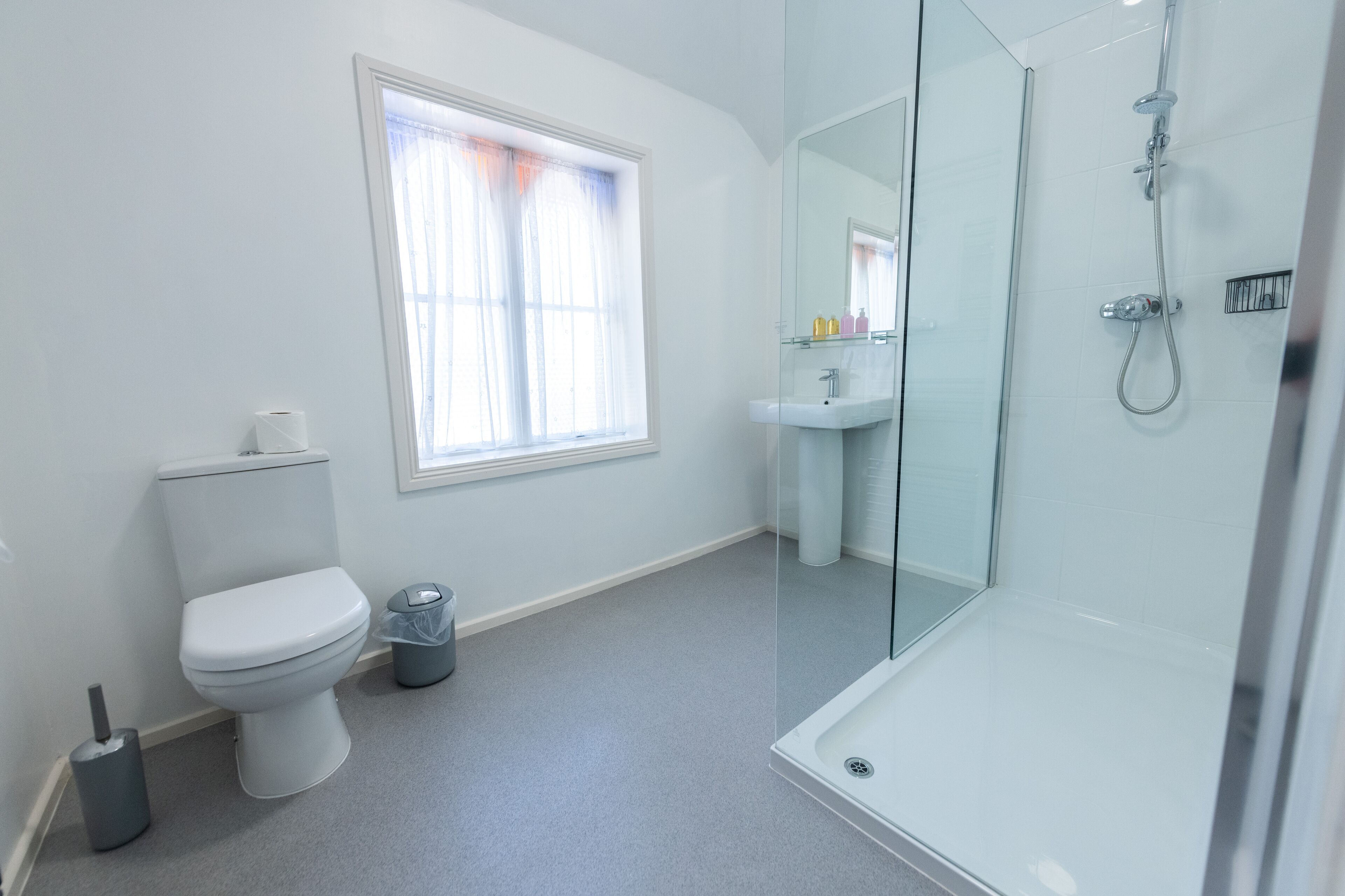 A modern bathroom with a toilet, sink, and glass-enclosed shower.