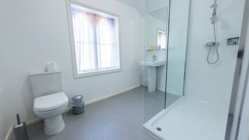 A modern bathroom with a toilet, sink, and glass-enclosed shower.
