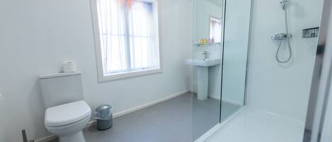 Een moderne badkamer met toilet, wastafel en douchecabine.