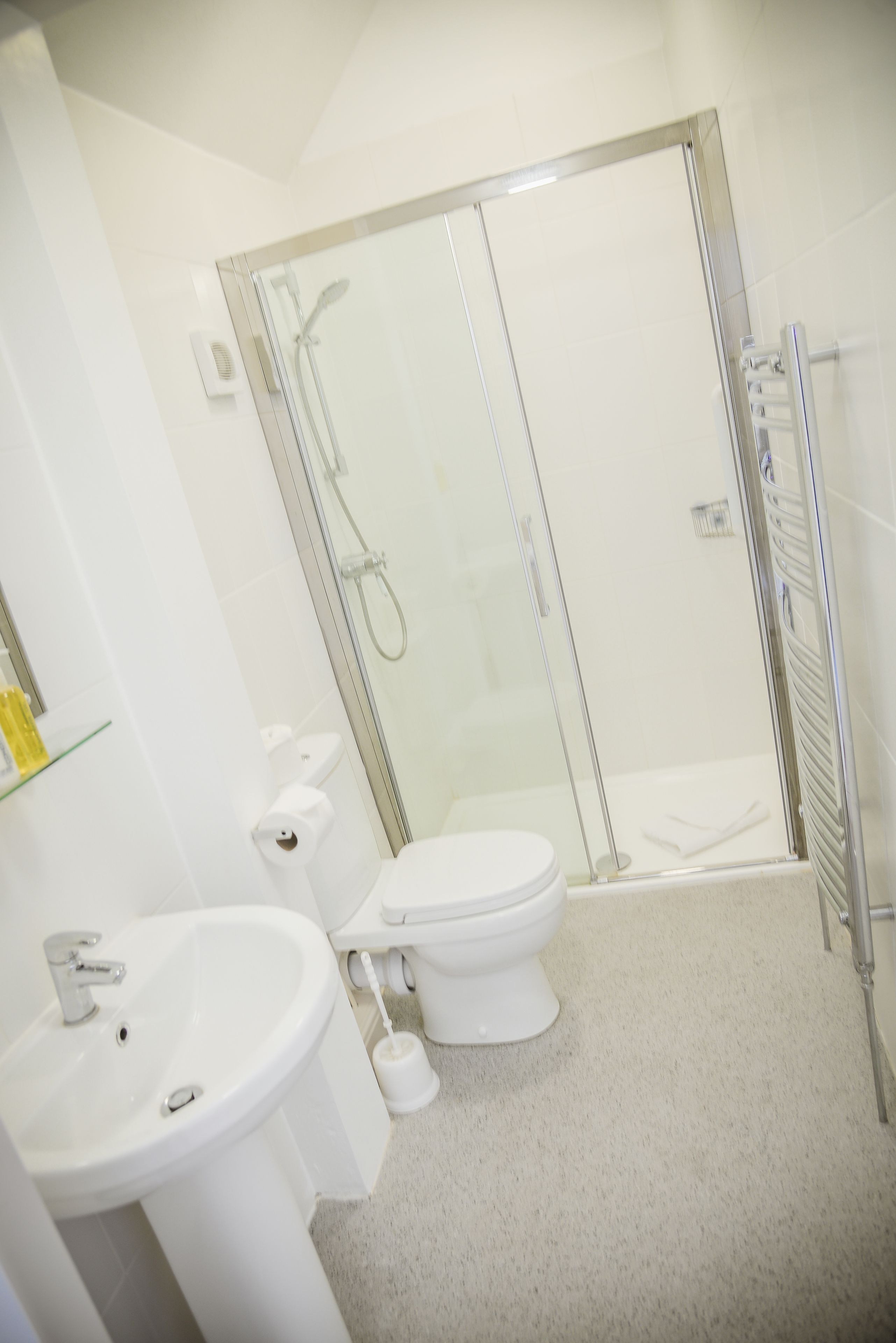 Een badkamer met douche, toilet en wastafel.