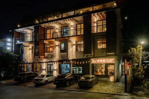 A multi-story building with a ground-level restaurant and several parked cars. - Tian's Resort (Zhangjiajie)