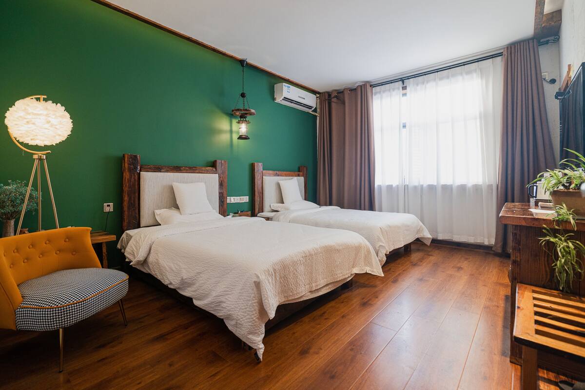Een kamer met twee bedden, een stoel, een bureau en een lamp.