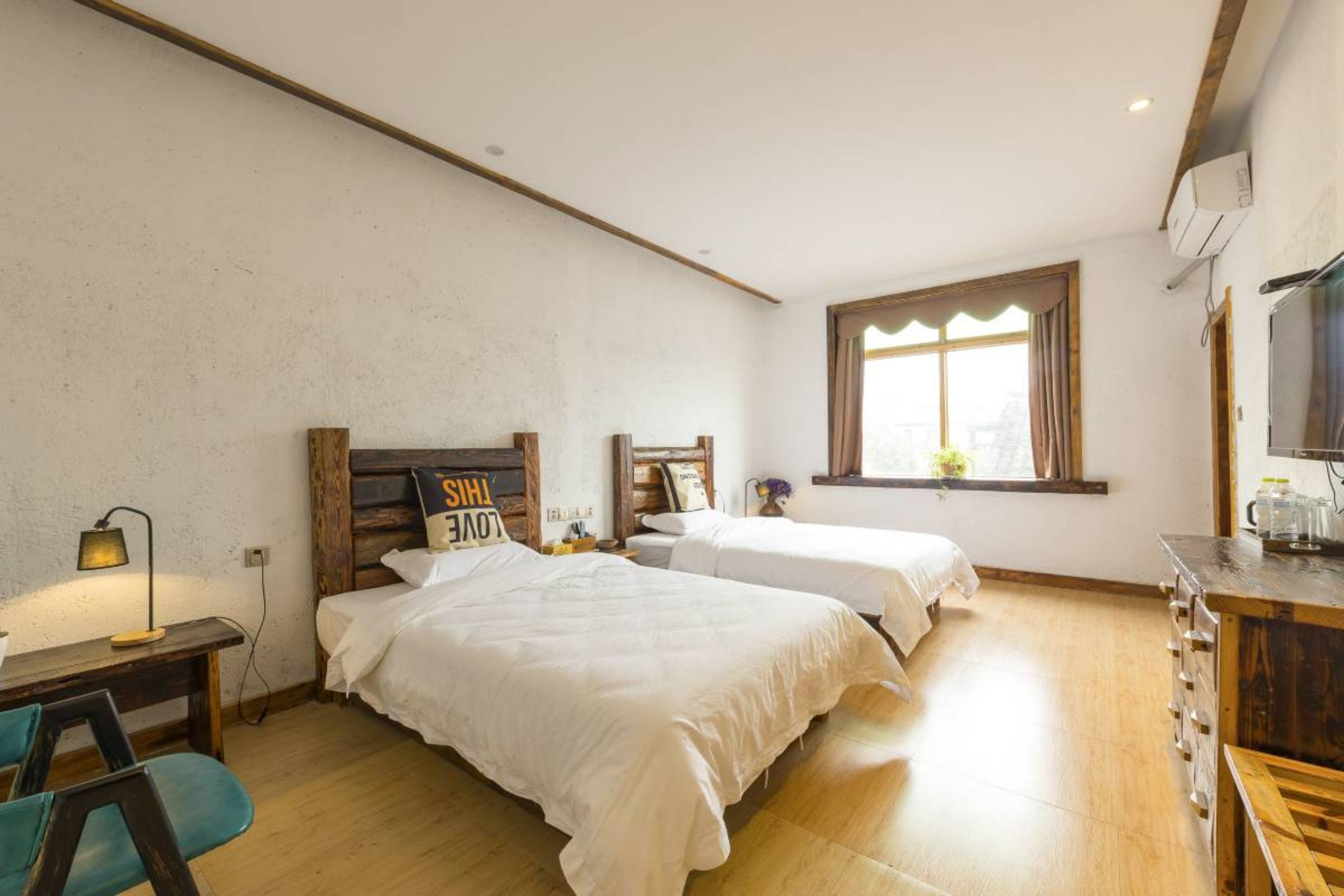 Un dormitorio con dos camas, un escritorio, una silla y una ventana con cortinas.