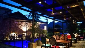 An outdoor dining area with stone walls, wooden tables, and chairs. - Tian's Resort (Zhangjiajie)