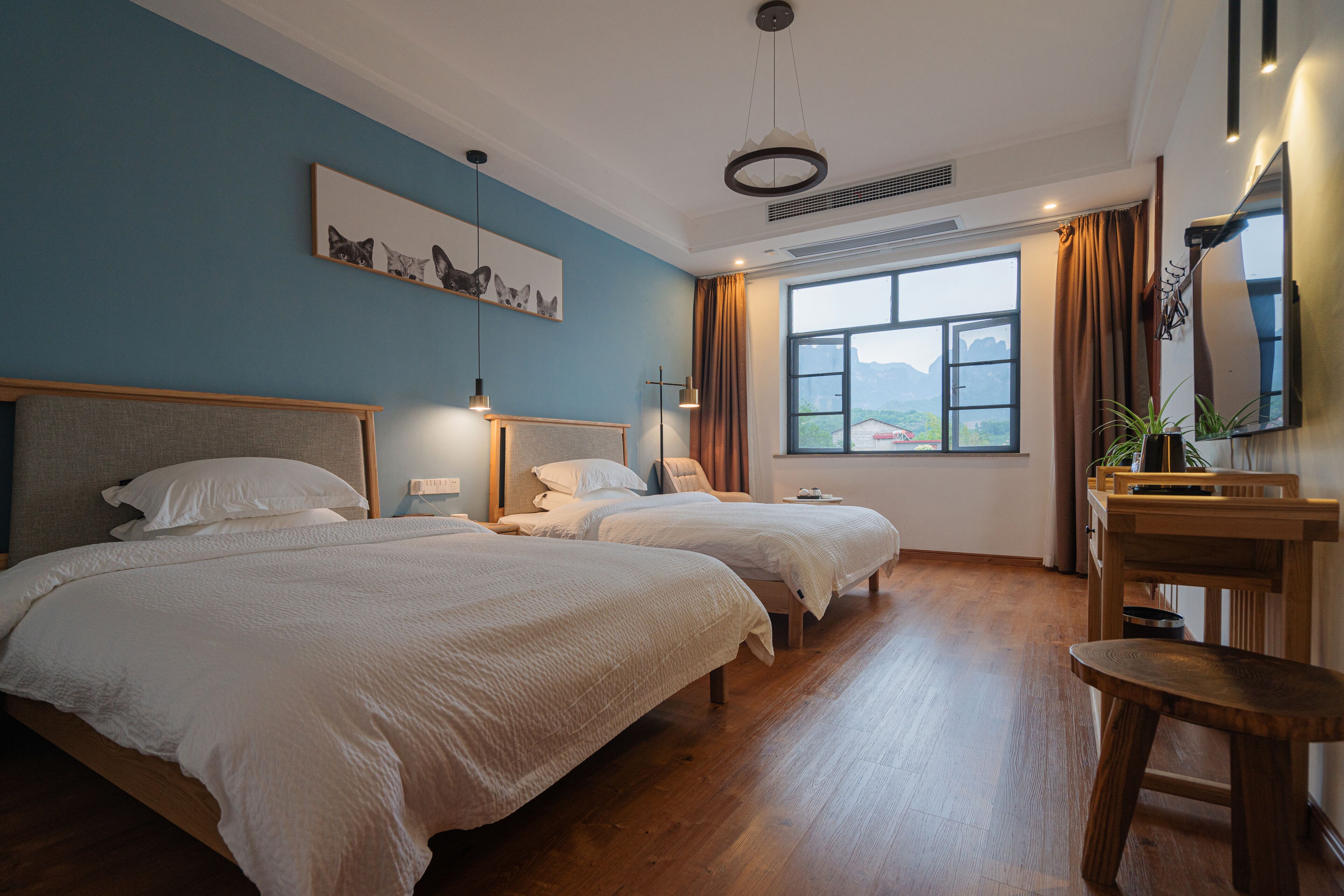Habitación de hotel con dos camas, un escritorio, una silla, una ventana con vistas y un televisor montado.