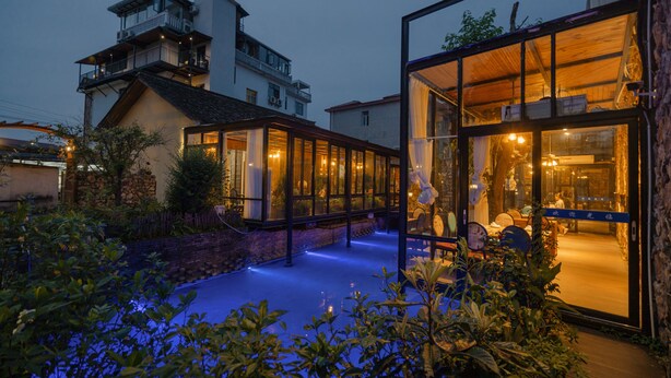 A modern building with large glass windows and a rooftop terrace. - Tian's Resort (Zhangjiajie)