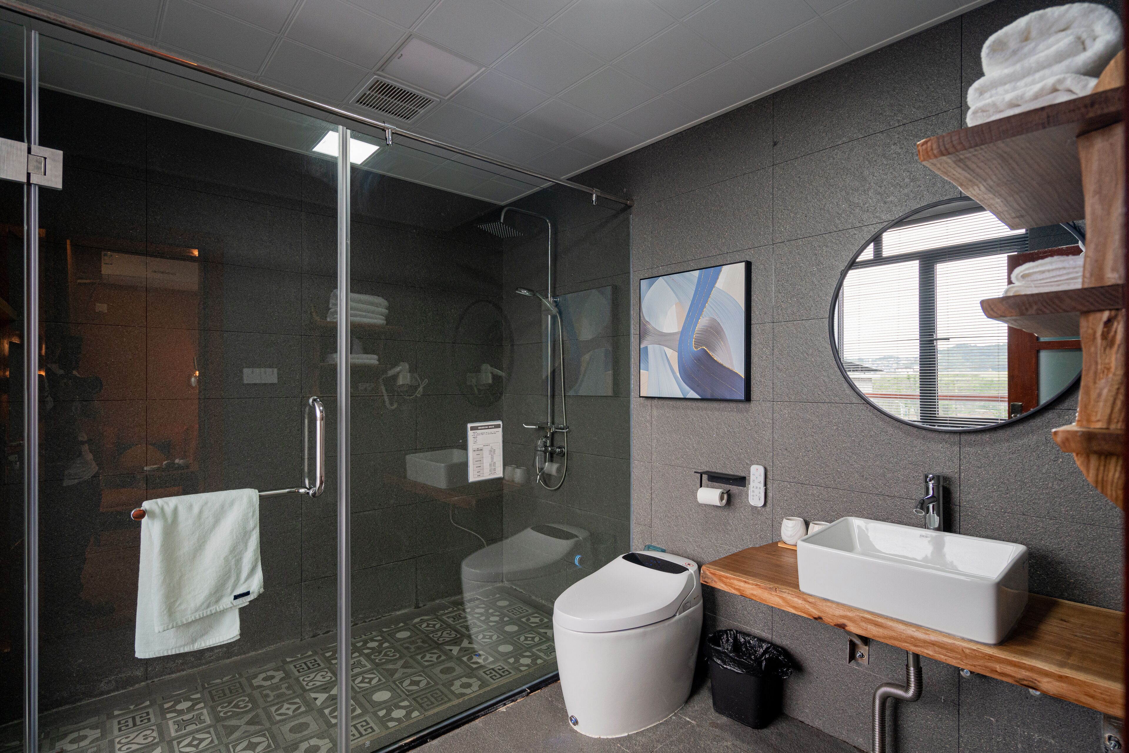 Un baño moderno con ducha envuelta en vidrio, inodoro, lavamanos y espejo.