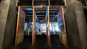 A restaurant with a modern interior, featuring a central dining area with tables and chairs, and a view of the street outside. - Tian's Resort (Zhangjiajie)