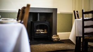 A room with a fireplace, a table with chairs, and a patterned wall. - Fir Tree B&B at Galvelbeg House (Crieff)