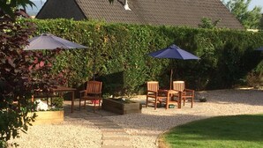 A patio area with a gravel path, wooden chairs, and two umbrellas. - Fir Tree B&B at Galvelbeg House (Crieff)