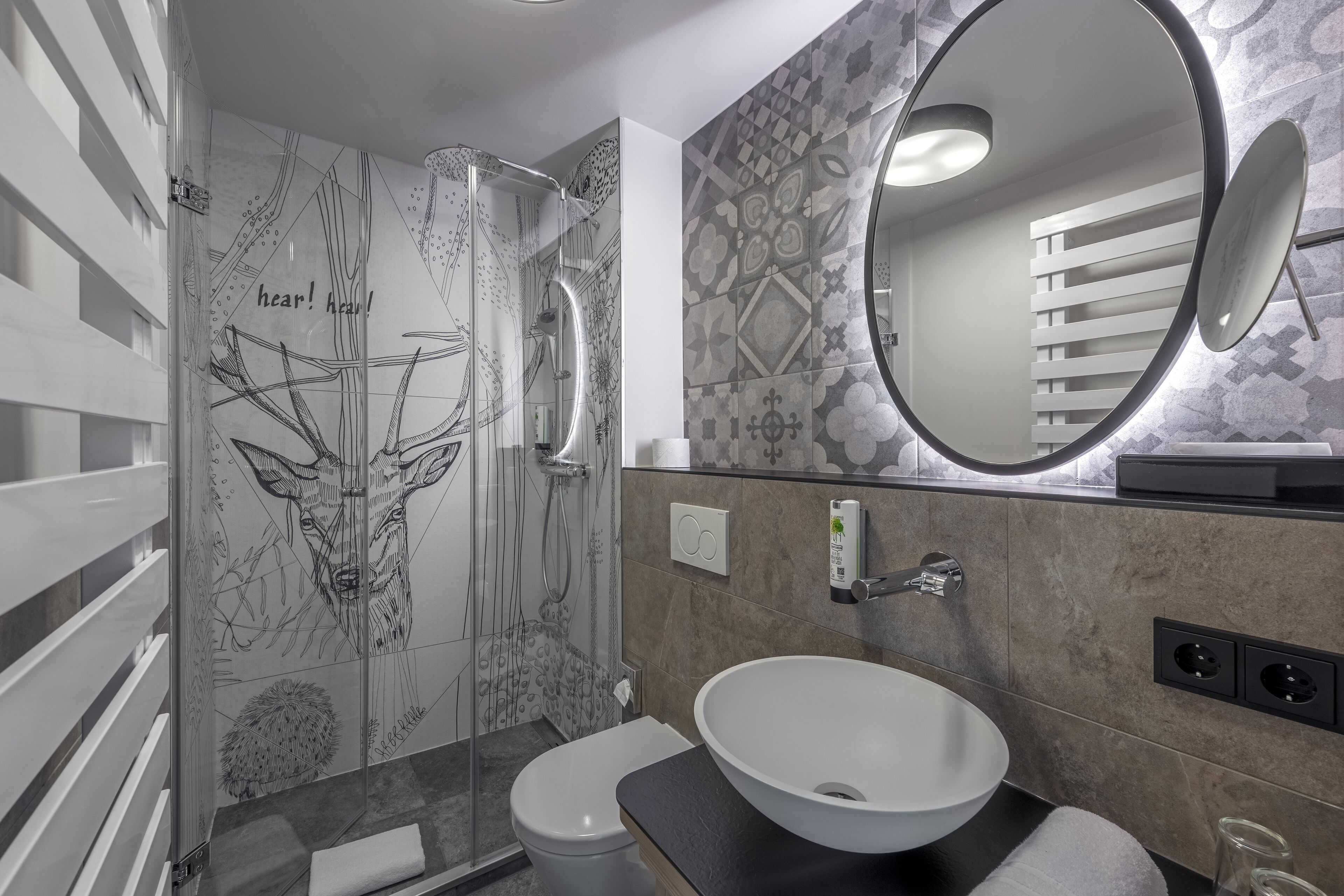 A modern bathroom with a glass shower, a white sink, and a large mirror.