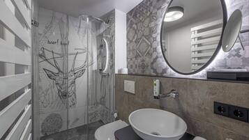 A modern bathroom with a glass shower, a white sink, and a large mirror.