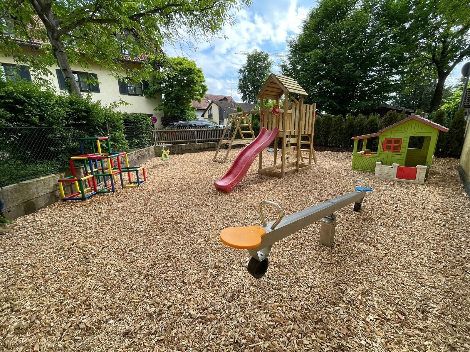 A playground with a slide, climbing structures, and a seesaw.
