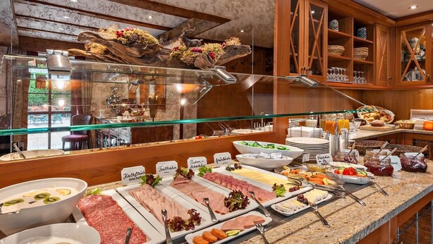 Ein Buffet mit verschiedenen Speisen, eine Glastheke und Holzschränke im Hintergrund.