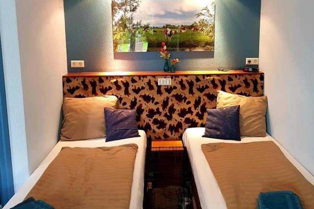 A room with two beds, a wall-mounted TV, and a ceiling light.
