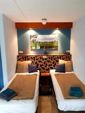 A room with two beds, a wall-mounted TV, and a ceiling light. - Boerderij Hazenveld (Kockengen)