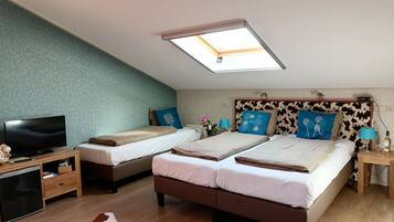 A bedroom with two beds, a TV, a small fridge, and a ceiling light.