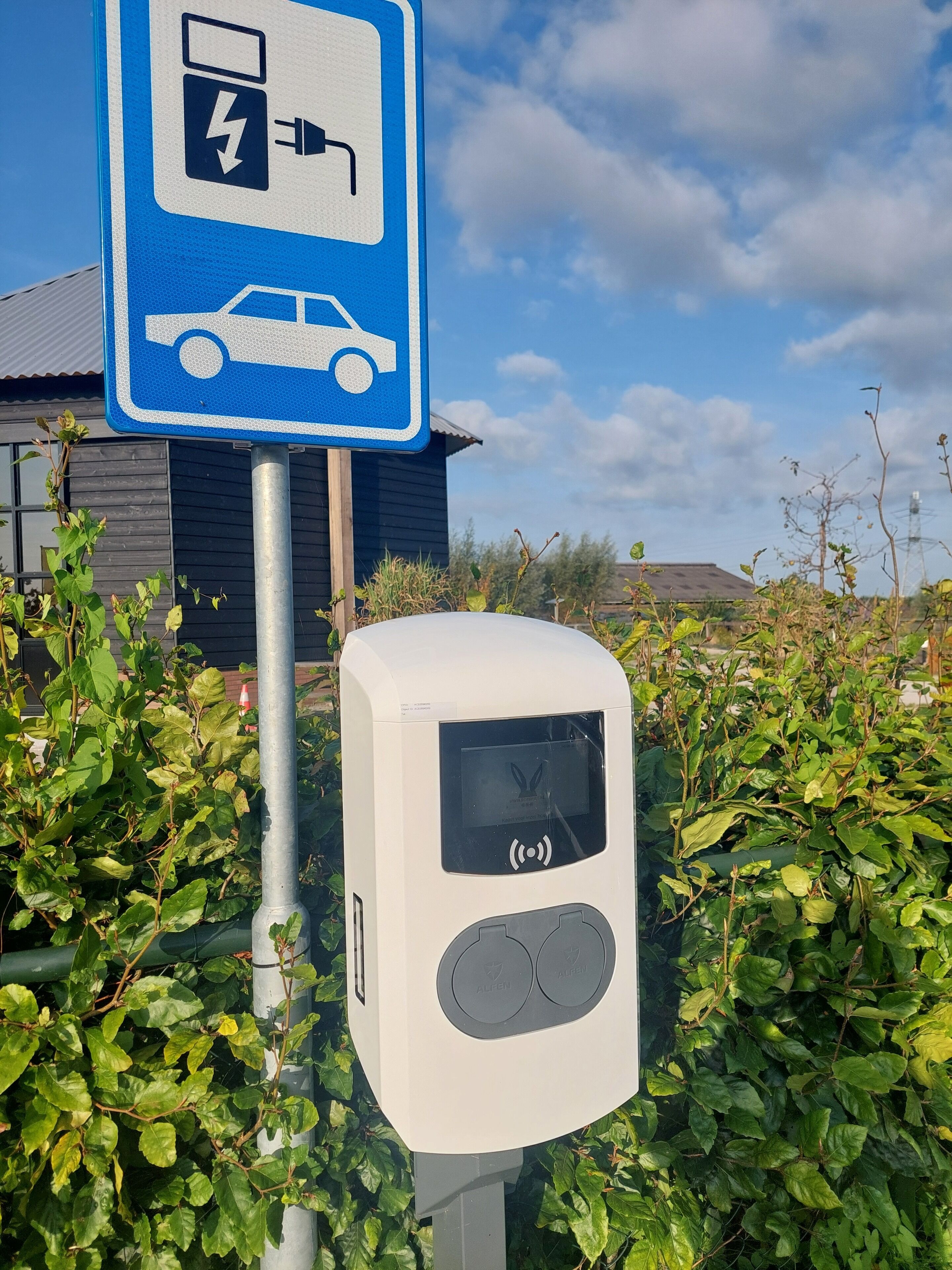Estación de carga para vehículos eléctricos con un letrero que indica la disponibilidad de un punto de recarga.